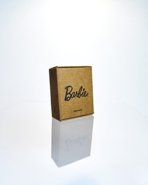 Caja kraft frontal del libro miniatura coleccionista escala 1:6 con logo Barbie impreso en negro.