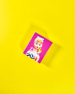 Muñeca de colección sosteniendo libro miniatura escala 1:6 sobre fondo rosa