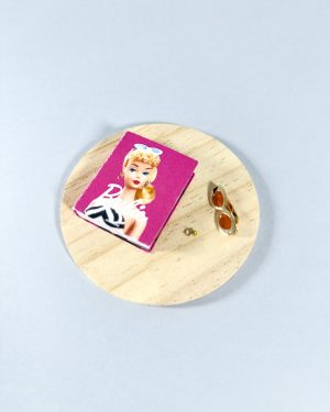 Libro miniatura escala 1:6 sobre mesa de madera con gafas doradas